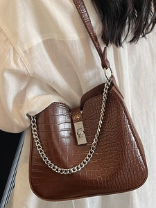 Brown crocodile pattern shoulder bag with silver chain and metal buckle on female model