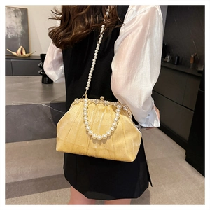 Detail of champagne gold evening clutch with pleated mesh and elegant pearl handle
