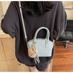 Detail of light blue crocodile pattern bucket bag with a cute plush bear charm decoration