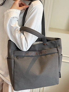 Dark grey canvas tote bag with shoulder straps and outer pockets for daily commuting