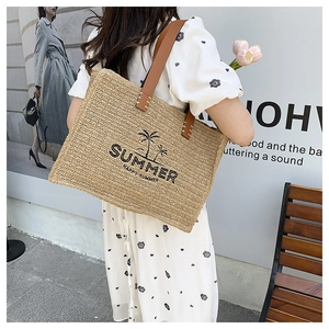 Outdoor shot of a woven straw tote with SUMMER text and palm tree on a model