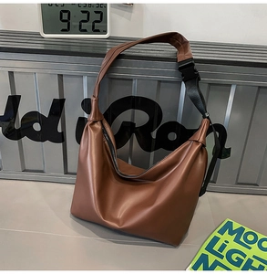 Close-up of brown faux leather tote with adjustable nylon strap and plastic buckle
