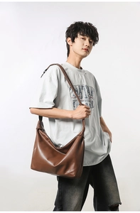 Detail of a large brown hobo crossbody bag in matte leather showing the soft drape