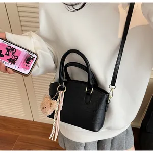 Detail of black crocodile texture mini bucket bag with teddy bear charm and strap