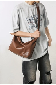Detail view of large dark brown matte faux leather tote bag worn as a crossbody bag