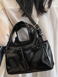 Glossy black patent leather handbag with dual front pockets and adjustable shoulder strap