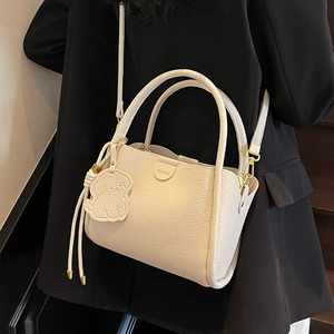 Sac à main élégant en cuir blanc cassé avec ferrures dorées et pendentif chien