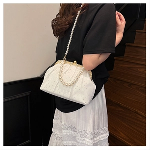Detail of white pleated evening bag featuring pearl chain and vintage gold clasp with rhinestones