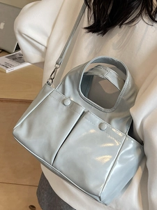 Light blue glossy faux leather shoulder bag with pockets shown on a stylish model
