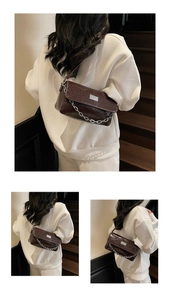 Close-up of deep brown glossy cracked leather baguette bag with silver chain strap details