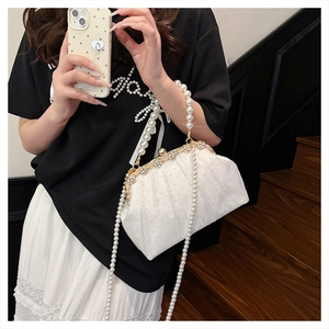 Detailed close-up of white pleated evening bag with pearl handle and vintage buckle