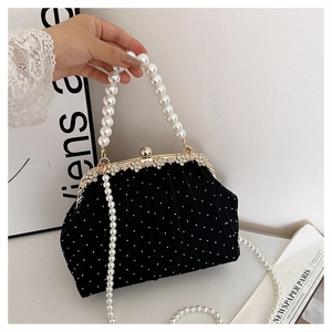 Close-up of black evening bag with diamond flowers, metal clasp, and pearl chain handle