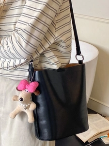 Modische schwarze Leder-Eimertasche mit süßem Welpenanhänger am Modell im Wohnambiente