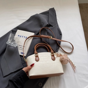 Detail of white crocodile texture bucket bag with brown handle and plush bear charm