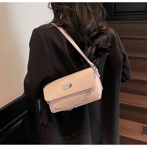 Fashionable light pink baguette bag with silver chain worn as a shoulder bag