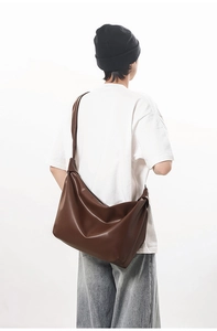 Detail view of large dark brown leather hobo bag with wide shoulder strap on model