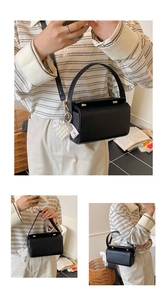Détail du sac à main boîte noir avec breloque cœur en perles et texture en cuir fin