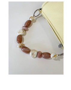 Close-up of marbled bead handle and yellow lychee texture leather on mini handbag