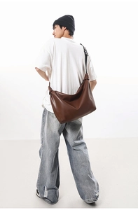 Brown faux leather tote bag worn by a model showing its large capacity and strap detail