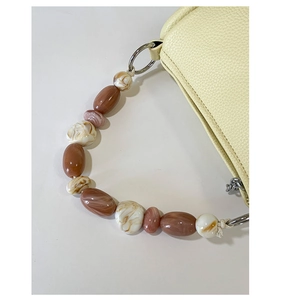 Detail of beaded handle with marble pattern acrylic beads on lychee leather bag