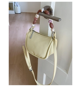 Detail view of lychee leather bucket bag with marble bead handle and adjustable strap