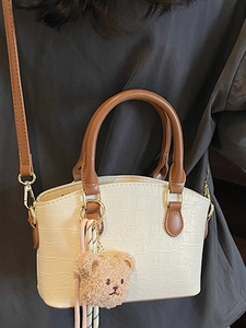 Chic beige crocodile pattern bucket bag with brown handles and a cute bear charm