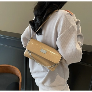 Close-up of khaki patent leather baguette bag with silver chain and textured finish