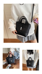 Detail view of black lychee grain tote bag showing metal twist lock and detachable strap