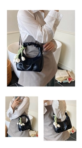 Détail du sac à main noir avec pendentif tulipe et poignée à texture froncée