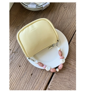 Detail view of yellow litchi leather bag with decorative marble resin beaded handle