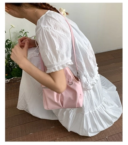 Detail of light pink nylon shoulder bag with adjustable strap on white summer dress