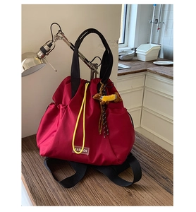 Detail of red nylon drawstring backpack with yellow cords and brown dachshund charm
