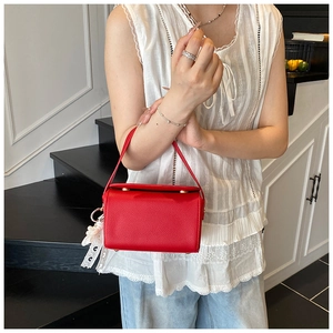 Détail du sac boîte en cuir grainé rouge avec une élégante décoration en dentelle