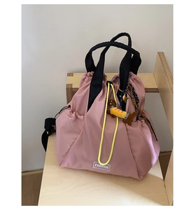 Detail of pink nylon drawstring backpack with contrast yellow cords and puppy pendant