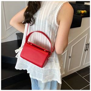 Détail du sac boîte rouge à texture litchi avec breloque perle et dentelle sur le mannequin