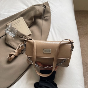 Macro shot of stylish beige faux leather baguette bag with silver chain and metal hardware