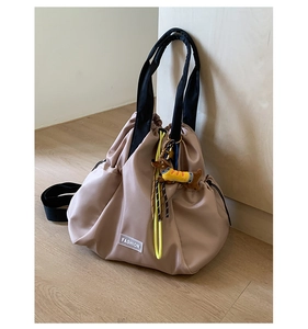 Detail of khaki nylon drawstring backpack with yellow cord and dog charm accessory