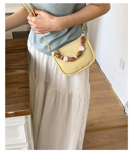 Detail of yellow mini crossbody bag featuring marble beaded chain and chic logo embossing