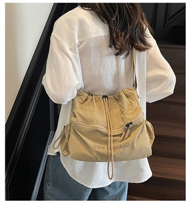 Detail view of khaki drawstring shoulder bag with pleat texture and YOU BEAR logo