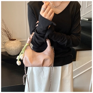 Détail du sac dumpling rose avec poignée plissée et pendentif tulipe blanche élégant
