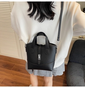 Detail of black litchi texture leather tote bag with silver metal swivel lock on the front