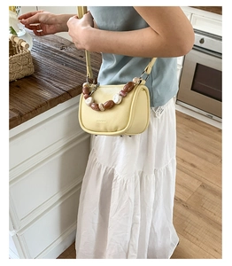 Detailed view of yellow lychee leather bucket bag with colorful resin beaded handle and metal feet