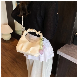 Sac boulette crème chic avec poignée froncée et breloque tulipe porté par un mannequin