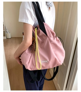 Detailed back view of pink nylon drawstring backpack with yellow cords on a model