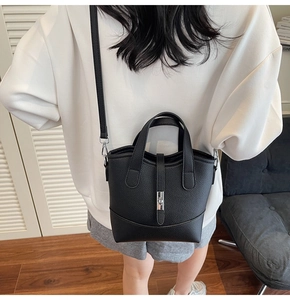 Close-up of black lychee grain leather bucket bag with silver buckle and crossbody strap