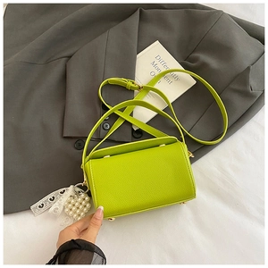 Détail du sac boîte vert fluo montrant la texture cuir grainé et le charme perle