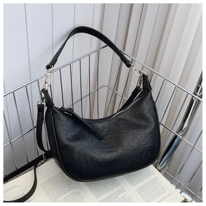 Detail of black crescent crossbody bag in wrinkled oil wax leather hanging in metal basket