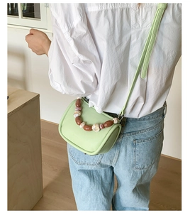 Close-up of mint green mini bag featuring decorative marble-textured beaded handle detail