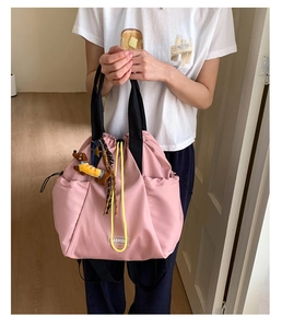 Pink nylon drawstring backpack detail with contrast yellow cords and dog plush charm