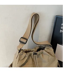 Close-up of khaki nylon drawstring crossbody bag with adjustable strap and stitched pocket